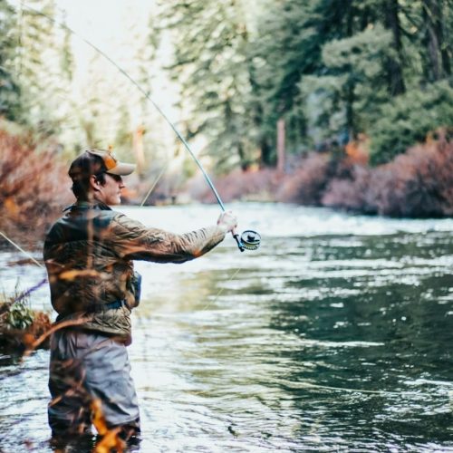 fly fisherman casting line in clear wilderness river