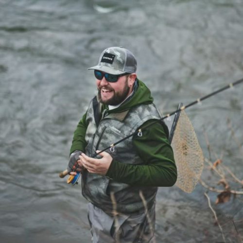 angler fly fishing in mountain river wilderness setting