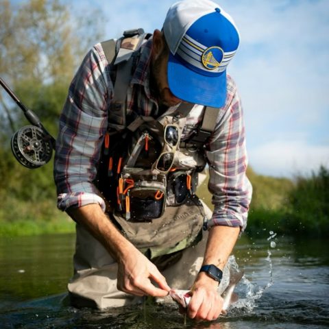 fisherman preparing catch beside remote mountain stream