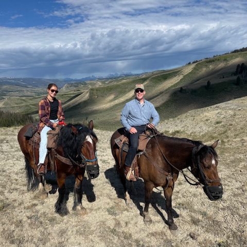 group horseback riding across open western landscape
