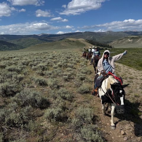 horseback riders traveling across high desert mountain plateau