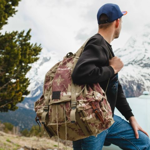man hiking through forest carrying backpack during wilderness trip